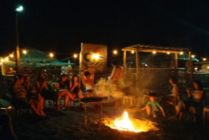 Gathered around a crackling bonfire at Beach Camp La Union, guests enjoy the warmth and camaraderie of a beachside evening. The flames dance against the night sky, casting a cozy glow on smiling faces. This image captures the essence of Beach Camp's inviting atmosphere, where beach bonfires create unforgettable memories under the stars.