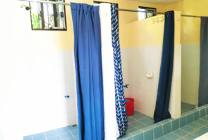 The exterior of Beach Camp's restroom facilities, characterized by its clean and inviting appearance. The building is surrounded by well-kept landscaping, with pathways leading to the entrance, ensuring easy access for guests. The design integrates seamlessly with the natural beach environment, highlighting the resort's dedication to cleanliness and environmental care.