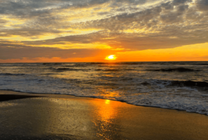 The serene coastline of La Union is illuminated by the soft, golden glow of the setting sun, as seen from Beach Camp, the premier beach resort for witnessing nature's daily masterpiece. The tranquil waters reflect the fiery colors of the sky, creating a mesmerizing scene that embodies the peaceful beauty of sunset at Beach Camp La Union.