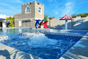 Nestled along the vibrant coast of La Union, this affordable beach resort presents an oasis of leisure and relaxation for travelers seeking both adventure and tranquility without breaking the bank. At the heart of the resort lies a sparkling pool, an inviting centerpiece surrounded by lush tropical foliage and sun-drenched loungers, where guests can dive into refreshing waters or bask in the warmth of the sun. The pool area, designed with aesthetic and comfort in mind, offers a panoramic view of the azure sea, blending seamlessly with the horizon. Accommodations at the resort are thoughtfully appointed, providing a cozy, welcoming ambiance that mirrors the natural beauty and serene atmosphere of the surroundings. With its prime location, guests have direct access to the pristine beach, where the gentle lapping of the waves and the golden sunset create a picturesque setting for relaxation and leisure. This resort proves that luxury and affordability can coexist, offering an idyllic coastal retreat where every guest can find their slice of paradise by the pool, under the sun, in beautiful La Union.