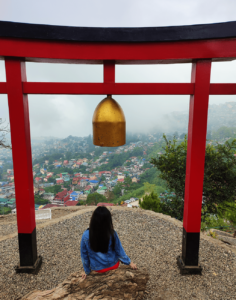 Torii Gate at Japanese Shrine in Baguio City: A serene and culturally rich image depicting the iconic Torii gate at a Japanese shrine in Baguio City, symbolizing a blend of cultures just an hour and thirty minutes away from Beach Camp, La Union. The photo captures the peaceful ambiance of the shrine, set against Baguio's lush greenery, highlighting the easy accessibility and diverse experiences available near Beach Camp.